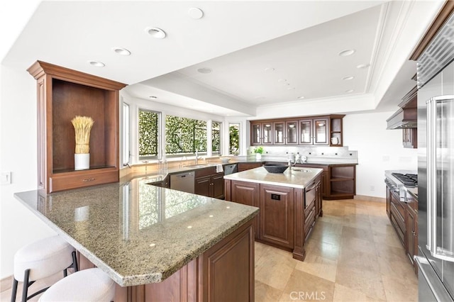 kitchen with a breakfast bar area, kitchen peninsula, a center island with sink, and stainless steel appliances