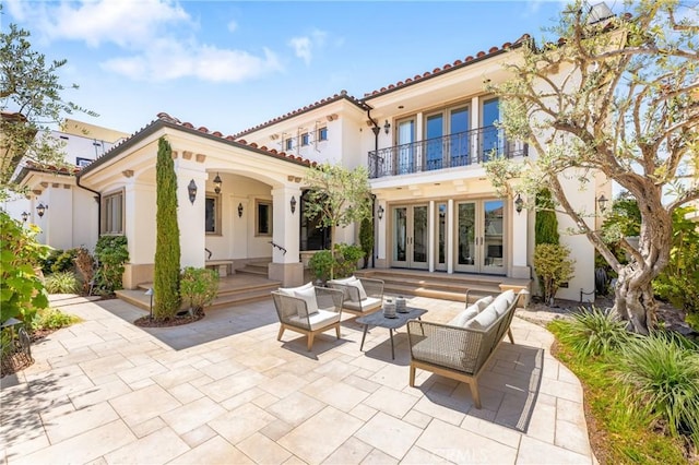 back of house with a patio area, an outdoor living space, a balcony, and french doors