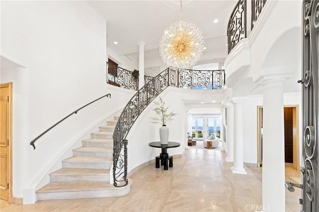 entryway with a high ceiling, decorative columns, and a notable chandelier