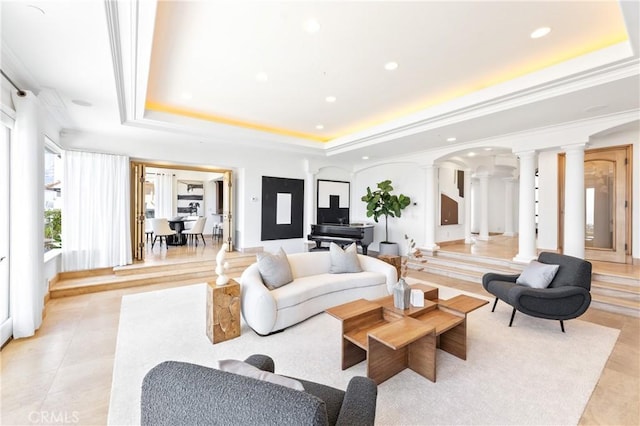 living room featuring a raised ceiling, decorative columns, and ornamental molding