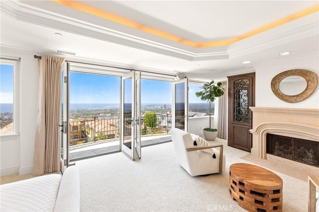 carpeted bedroom with a raised ceiling, crown molding, access to outside, and multiple windows