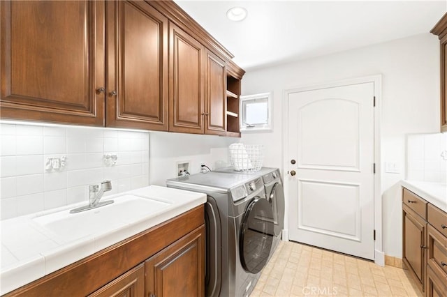 clothes washing area with cabinets, sink, and washing machine and clothes dryer