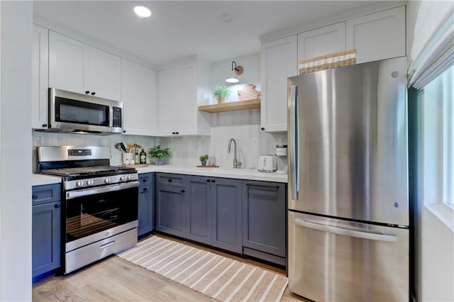 387 Cypress Dr Unit 7, Laguna Beach, CA 92651 - kitchen featuring appliances with stainless steel finishes, a sink, open shelves, light countertops, and decorative backsplash