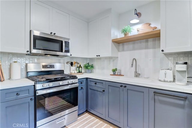 kitchen with white cabinets, backsplash, sink, and appliances with stainless steel finishes