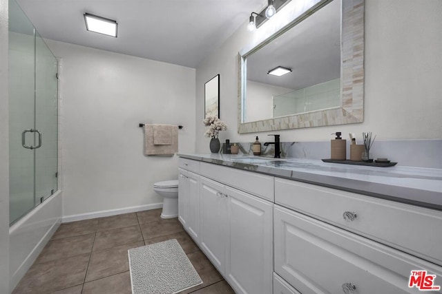 full bathroom with bath / shower combo with glass door, tile patterned floors, vanity, and toilet