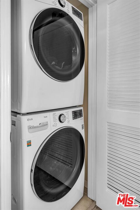 laundry room featuring stacked washer and clothes dryer and light tile patterned floors