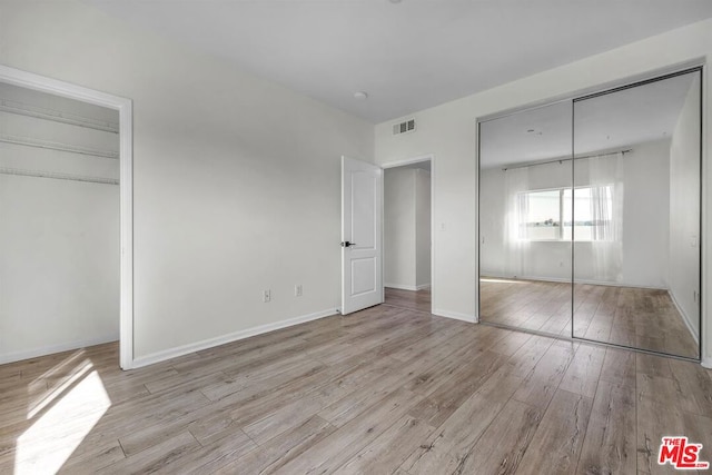 unfurnished bedroom featuring a closet and light hardwood / wood-style floors