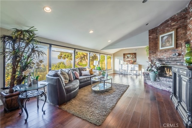 living room with a brick fireplace, lofted ceiling, and dark wood-type flooring