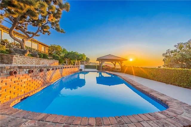 pool at dusk featuring a gazebo