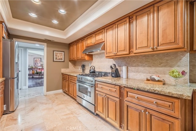 kitchen with tasteful backsplash, a tray ceiling, light stone counters, ornamental molding, and appliances with stainless steel finishes