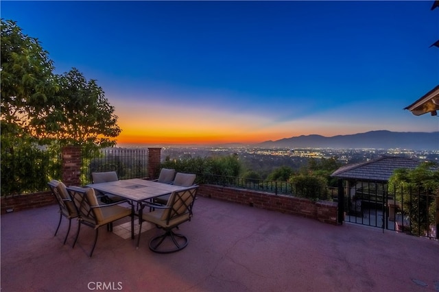 patio terrace at dusk featuring a mountain view