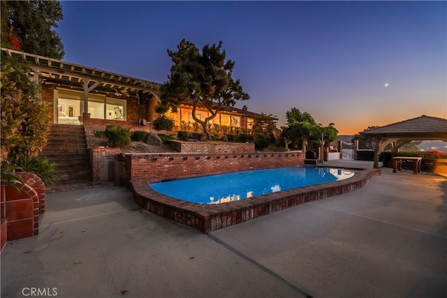 pool at dusk featuring a gazebo and a patio area