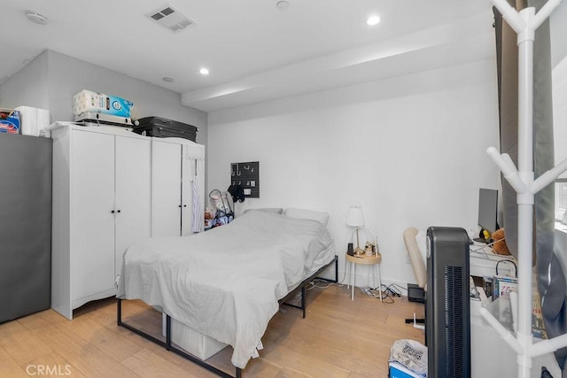 bedroom with stainless steel fridge and light wood-type flooring