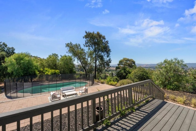 wooden terrace with a fenced in pool and a patio area