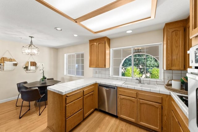 kitchen with pendant lighting, light hardwood / wood-style floors, kitchen peninsula, an inviting chandelier, and stainless steel dishwasher