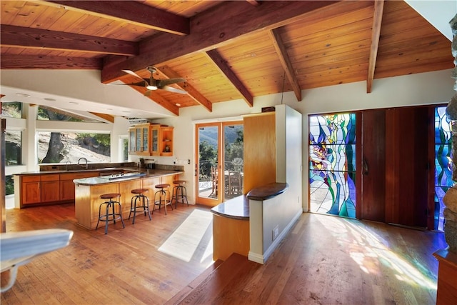 kitchen with a kitchen breakfast bar, kitchen peninsula, a wealth of natural light, and vaulted ceiling with beams