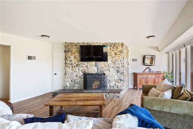 living room featuring a stone fireplace and wood-type flooring