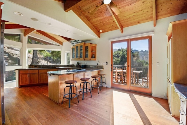 kitchen with kitchen peninsula, wood-type flooring, and vaulted ceiling with beams