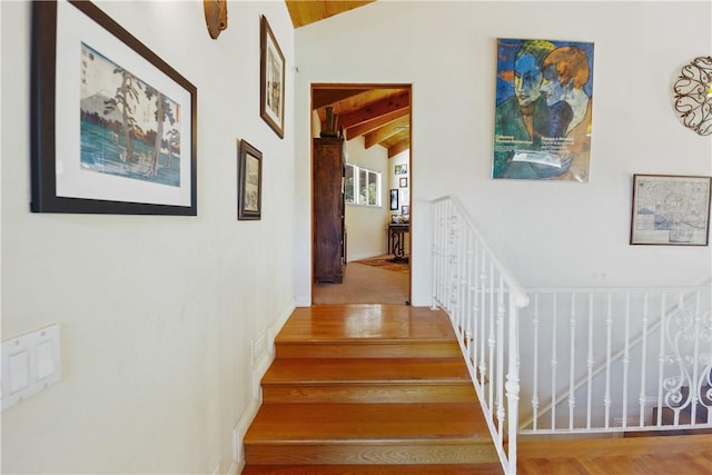 staircase featuring hardwood / wood-style floors and lofted ceiling with beams