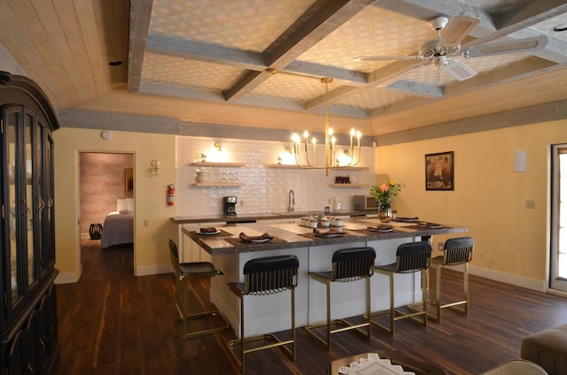 kitchen featuring a kitchen bar, dark hardwood / wood-style floors, beamed ceiling, ceiling fan with notable chandelier, and decorative light fixtures