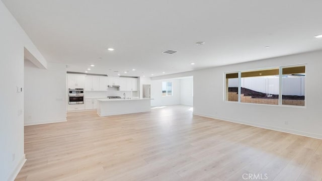 unfurnished living room with sink and light hardwood / wood-style flooring