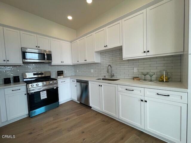 kitchen with sink, white cabinets, appliances with stainless steel finishes, and tasteful backsplash