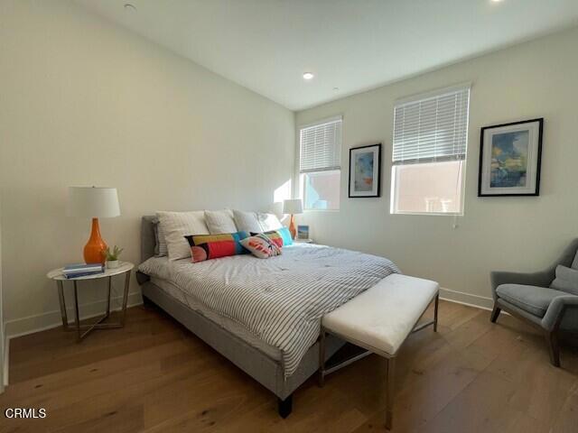 bedroom with baseboards, wood finished floors, and recessed lighting