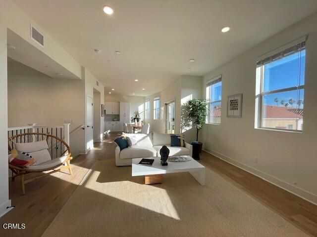 living area featuring recessed lighting, visible vents, baseboards, and wood finished floors