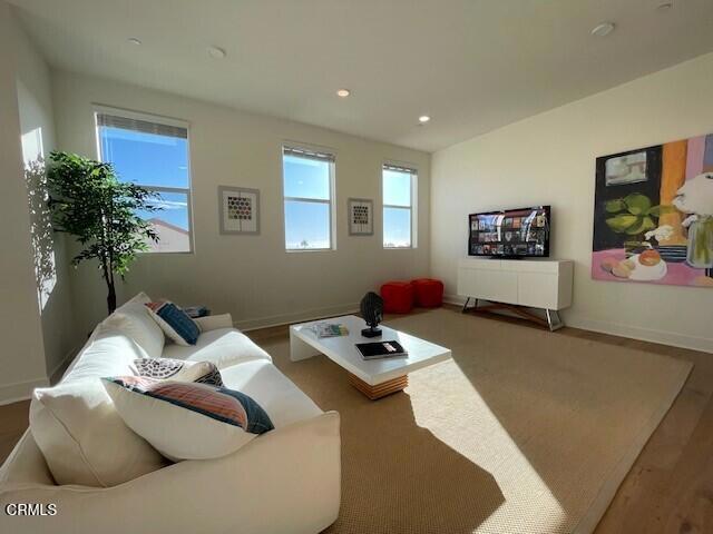 living area with baseboards, wood finished floors, and recessed lighting