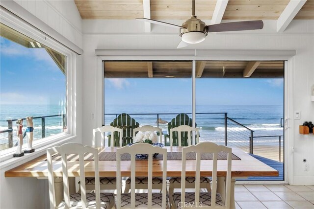 dining room featuring ceiling fan, light tile patterned floors, a water view, and a healthy amount of sunlight