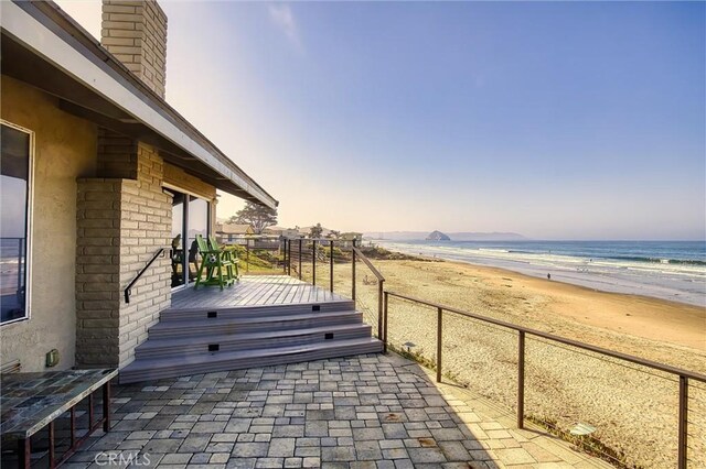 patio terrace at dusk with a view of the beach and a deck with water view