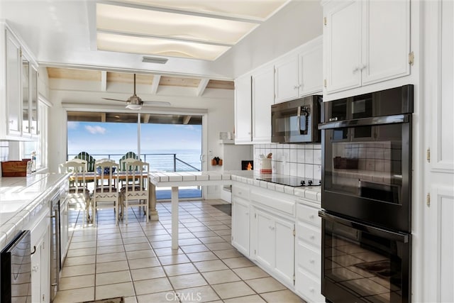 kitchen with ceiling fan, backsplash, black appliances, tile countertops, and a water view