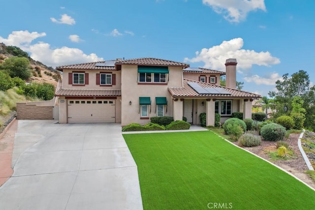 mediterranean / spanish-style home with a garage, a front lawn, and solar panels