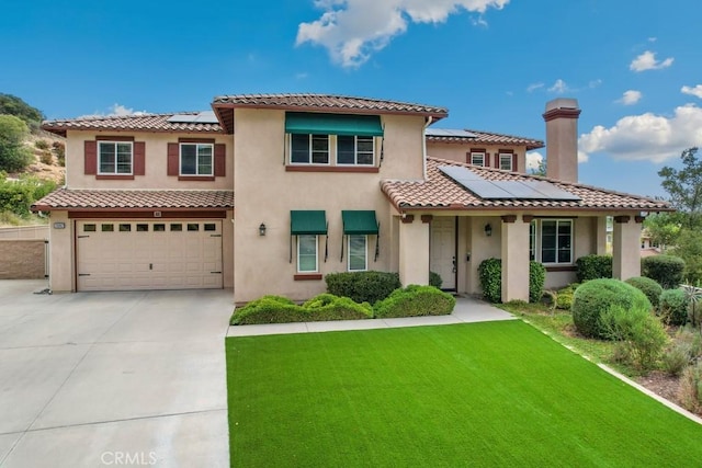 mediterranean / spanish home with solar panels, a front yard, and a garage