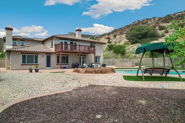 back of property with a mountain view, a balcony, a patio, and a fenced in pool