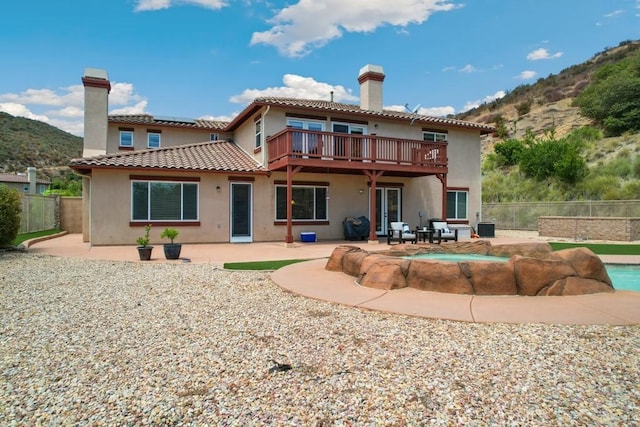 back of property with a mountain view, a fenced in pool, and a patio