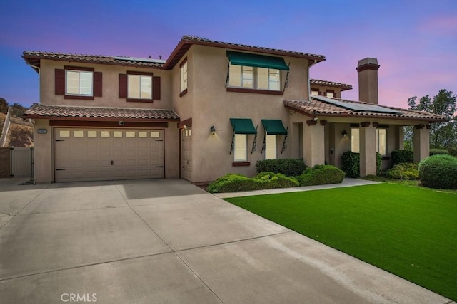 mediterranean / spanish-style home featuring a yard and a garage