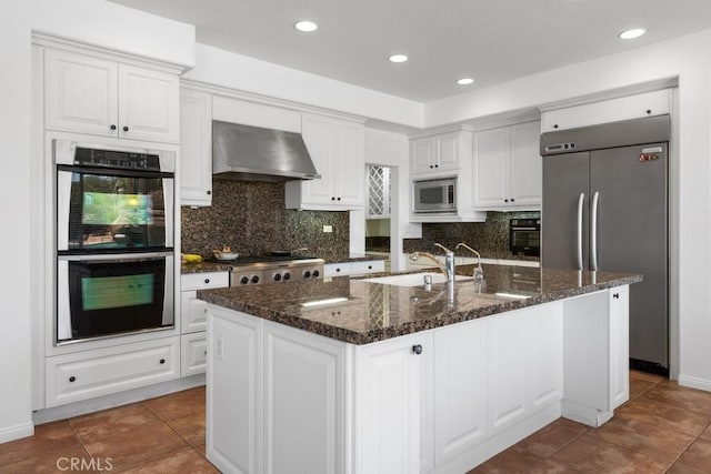 kitchen featuring extractor fan, stainless steel appliances, an island with sink, white cabinetry, and sink