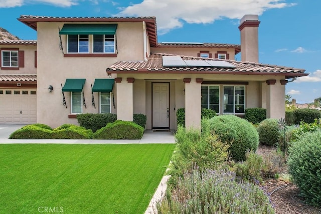 mediterranean / spanish-style home with a front yard, a garage, and solar panels