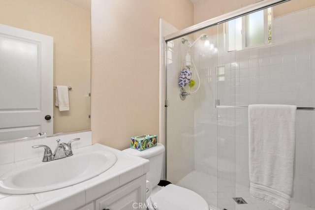 bathroom with toilet, a shower with shower door, and vanity