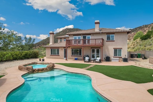 rear view of house with a pool with hot tub, a balcony, a patio, and central AC