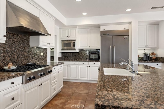 kitchen with stainless steel appliances, white cabinetry, sink, and wall chimney exhaust hood