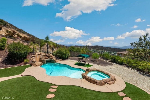 view of pool featuring a lawn, an in ground hot tub, and a mountain view