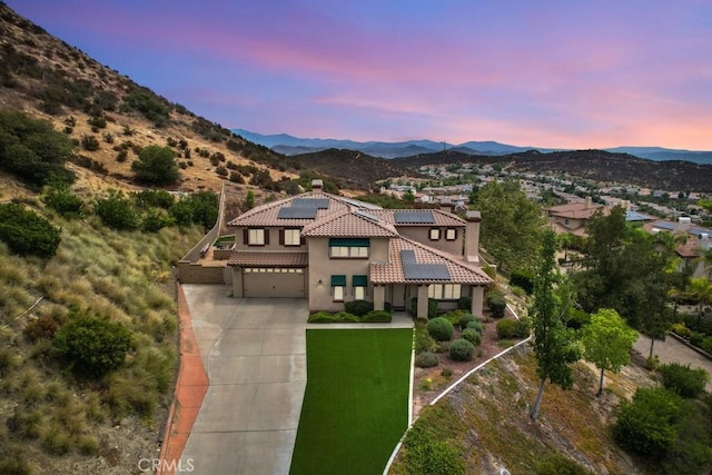 mediterranean / spanish-style house featuring solar panels, a garage, a yard, and a mountain view