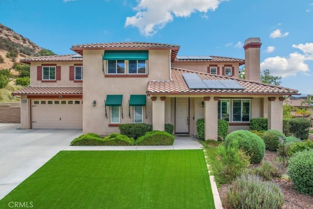 mediterranean / spanish-style home featuring a front yard, a garage, and solar panels