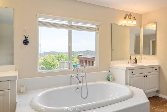 bathroom with a relaxing tiled tub, tile patterned floors, a mountain view, and vanity