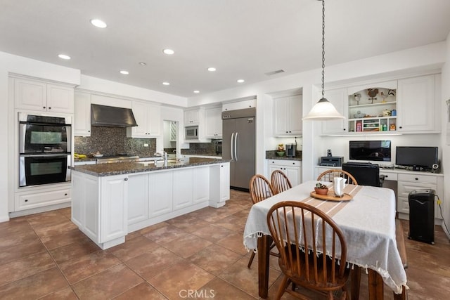 kitchen with built in appliances, an island with sink, extractor fan, and white cabinets