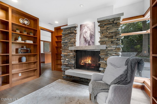 living area with a fireplace, wood-type flooring, and plenty of natural light