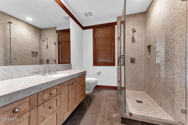 bathroom featuring toilet, vanity, and a shower with door