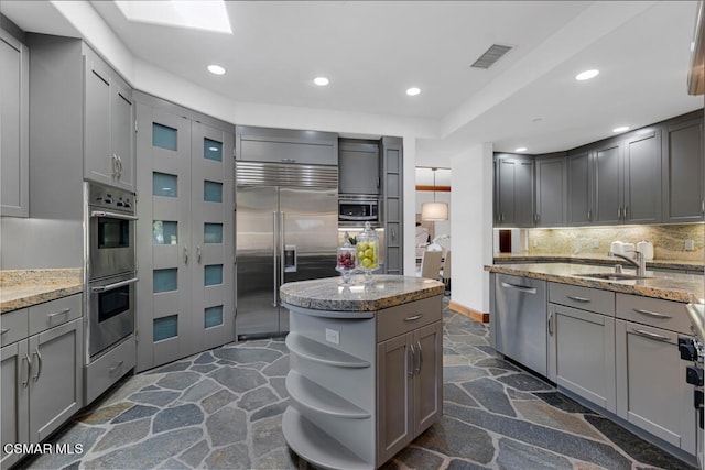 kitchen with stainless steel appliances, decorative backsplash, sink, and gray cabinets